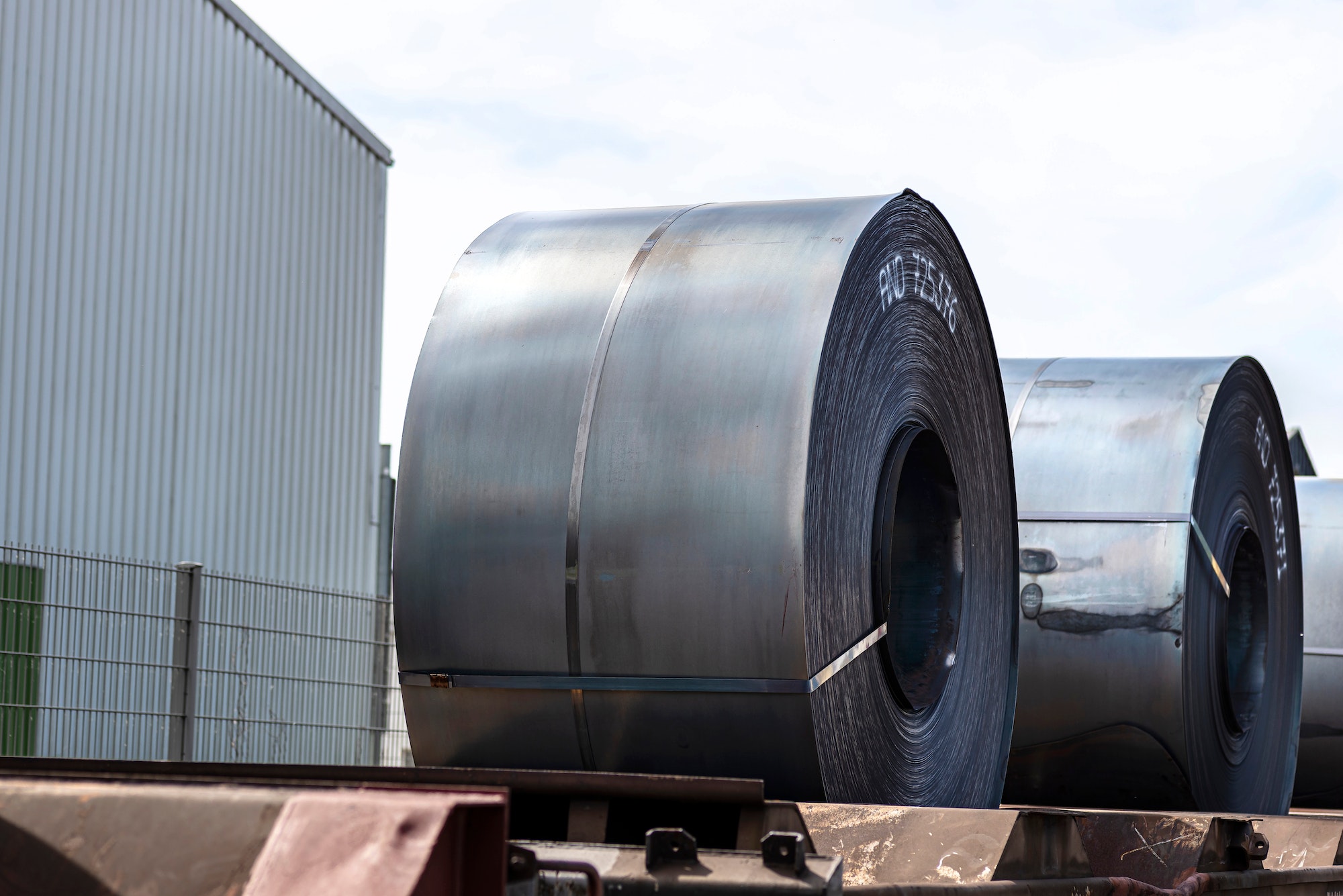 Large rolls of sheet metal lying on a freight wagon pulled by locomotives.