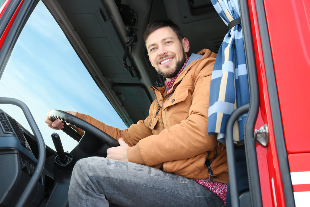 Ein LKW-Fahrer schaut freundlich aus seinem Fahrerhaus.