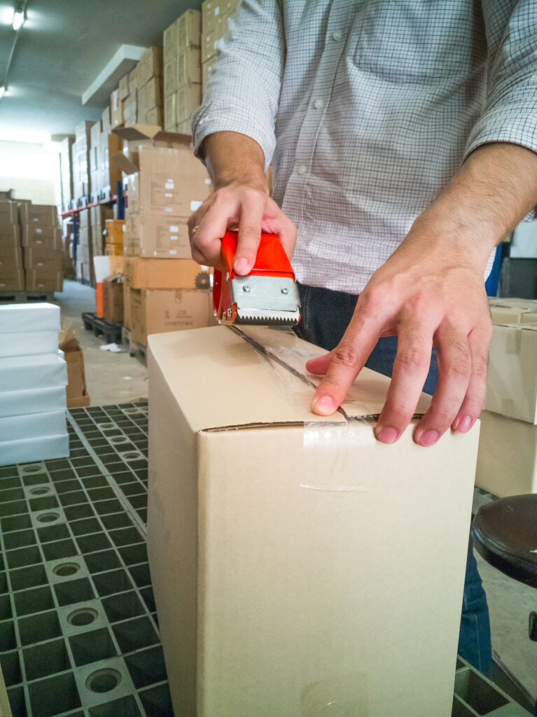 Lagermitarbeiter beim Verpacken von Ware in ein Paket - ein Value Added Service von Maintrans.