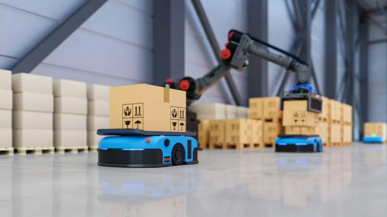 In einem automatisierten Lager belädt ein Roboterarm fahrerlose Transportsysteme mit Paketen.