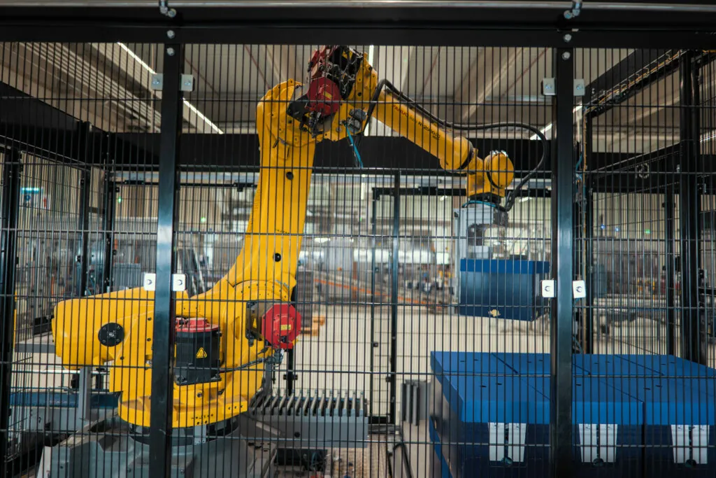 Gelber Roboterarm stapelt Kisten in einem automatisierten Logistik-Lager.
