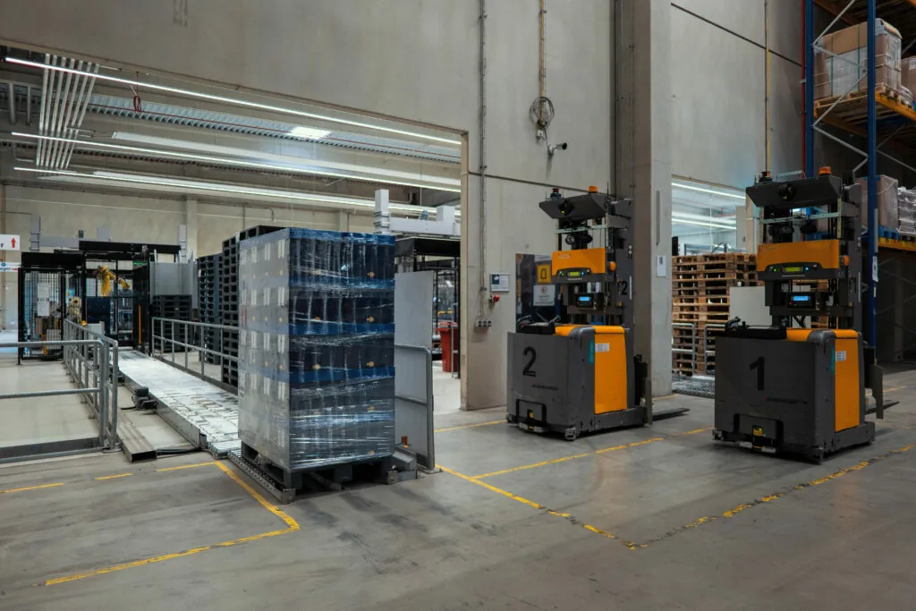 Zwei fahrerlose Transportsysteme warten auf Ihren Einsatz in einem automatisierten Logistik-Lager.