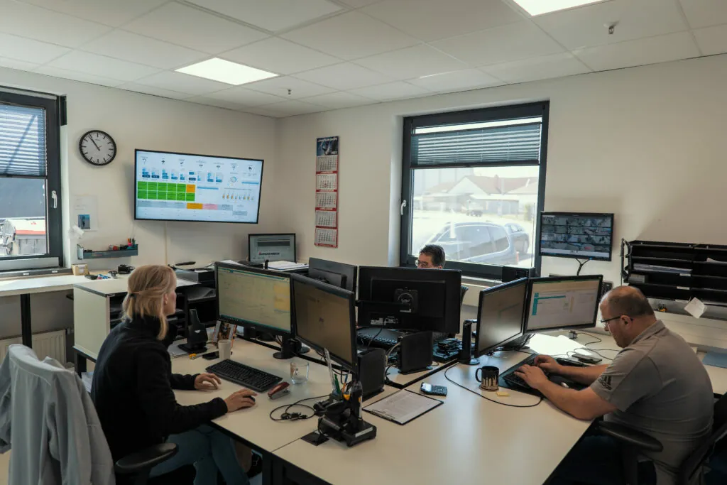 Drei unserer Mitarbeiter arbeiten mit dem Warehousemanagementsystem am PC.